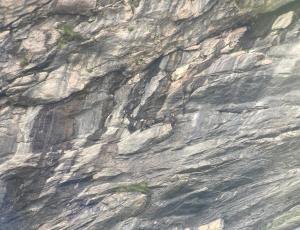 Gaia, Aurora und Paradiso (von links nach rechts) übernachten zu dritt auf einem Felsvorsprung in einer steilen Felswand.